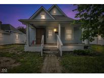 Cozy blue house boasting a covered front porch with columns and updated windows against a colorful sky at 1617 E Kelly St, Indianapolis, IN 46203
