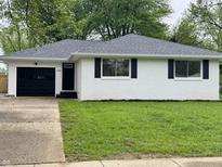 Charming white brick home with black shutters, complemented by a well-maintained lawn and black garage door at 2431 Timbercrest Dr, Columbus, IN 47203