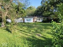 View of a single-story home with white siding and a spacious, lush front yard surrounded by mature trees at 2928 Cicero Rd, Noblesville, IN 46060