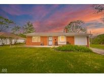 Charming red brick home featuring a well-manicured lawn and inviting front porch with seating at 3846 Alsace Pl, Indianapolis, IN 46226