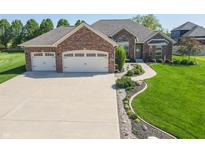 Beautiful brick home featuring a three-car garage, manicured lawn, and appealing landscaping at 6077 W David Wayne Dr, New Palestine, IN 46163