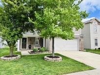 Charming home featuring a two-car garage, well-maintained lawn, and beautiful mature trees at 7804 Amadeus Dr, Indianapolis, IN 46239