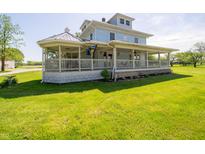Charming two-story home showcasing a spacious wrap-around porch and lush green lawn at 9579 N Fortville Pike, Fortville, IN 46040