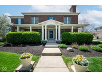 Charming red brick home with covered front porch, blue door, and well-manicured landscaping at 1787 Halifax St, Carmel, IN 46032