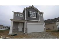Charming two-story home featuring a gray exterior, stone accents, a two-car garage and a covered front entry at 1874 Victor Higgins Dr, Shelbyville, IN 46176