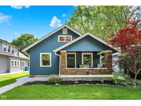 Charming blue home featuring a cozy front porch, manicured lawn, and vibrant landscaping, creating an inviting curb appeal at 5015 Carrollton Ave, Indianapolis, IN 46205