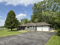 Ranch-style home with a two-car garage, gray siding, and an asphalt driveway surrounded by a well-manicured lawn at 7897 Moore Rd, Indianapolis, IN 46278
