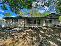 Ranch style home with stone and siding, neutral colors, mature trees, and a covered front porch at 3401 W Kessler Blvd N Dr, Indianapolis, IN 46222