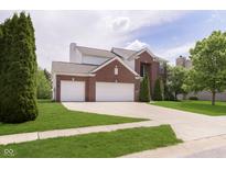 Attractive two-story brick home featuring a well-kept lawn, mature tree, and a convenient attached two-car garage at 6839 Powder Dr, Indianapolis, IN 46259
