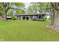 Charming single-story home with gray brick, well-manicured lawn, mature trees, and a welcoming front porch at 7228 Kimberly Ln, Plainfield, IN 46168