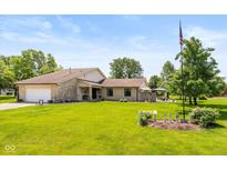 Charming stone home featuring a well-manicured lawn and a decorative American flag at 8111 Timberwood Dr, Plainfield, IN 46168