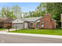Charming single-story home with a brick chimney, gray siding, well-maintained lawn, and an attached two-car garage at 12290 Charing Cross Rd, Carmel, IN 46033