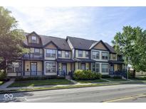 Charming townhome featuring a yellow exterior with blue trim, a private balcony, and a well-maintained front yard at 2260 Central Ave, Indianapolis, IN 46205