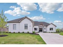 Stunning, white brick home with a well-manicured lawn and a concrete driveway at 5667 Skylark Dr, Greenwood, IN 46143