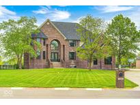 Majestic brick home featuring a well-manicured lawn and a charming water fountain at 16285 Remington Dr, Fishers, IN 46037