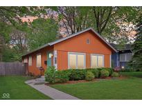 Charming orange single-story home featuring a well-manicured lawn and a vibrant blue door at 4810 Winthrop Ave, Indianapolis, IN 46205