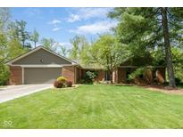 Charming brick home with a spacious front yard and mature landscaping, including a two-car garage at 7420 Denton Cir, Indianapolis, IN 46256