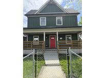 Charming two-story home featuring a bright red front door, a covered porch, and a fenced front yard at 209 N Beville N Ave, Indianapolis, IN 46201