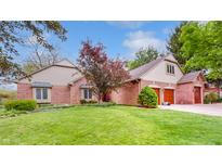 Charming brick home featuring an attached two car garage, manicured lawn, and mature trees at 265 Monticello Dr, Greenwood, IN 46142