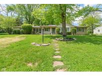 Charming ranch home with a stone walkway and a lush green lawn surrounded by mature trees at 5648 Rolling Ridge Rd, Indianapolis, IN 46220