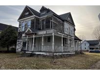 Two story home with covered front porch in need of some TLC and exterior paint at 802 S Anderson St, Elwood, IN 46036