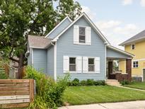 Quaint two-story home with light blue siding, white trim, and a lush green lawn with mature trees at 809 N Temple Ave, Indianapolis, IN 46201
