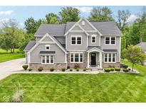 Beautiful two-story home with a stone and siding exterior, lush green lawn, and manicured landscaping at 9155 Kerwood Dr, Indianapolis, IN 46240