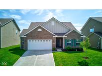 Charming brick home with a well-manicured lawn and two-car garage on a sunny day at 9823 Pica Dr, Fishers, IN 46040