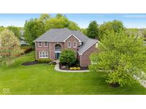 Charming two-story brick home featuring a manicured front lawn and mature trees at 13248 Blacktern Way, Carmel, IN 46033