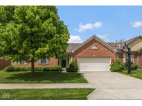 Charming brick home featuring a well-manicured lawn, mature tree, and a two-car garage at 14018 Powder Dr, Carmel, IN 46033