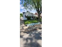 Charming single-Gathering home with black and white striped awnings and an overgrown front lawn at 1632 W 8Th W St, Anderson, IN 46016