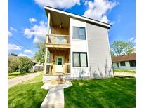 Modern two-story home with a wood balcony, gray siding, and a well-manicured lawn at 1721 Thaddeus St, Indianapolis, IN 46203