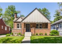 Charming brick home featuring a symmetrical design, covered porch, manicured lawn, and classic architectural details at 5912 Evanston Ave, Indianapolis, IN 46220