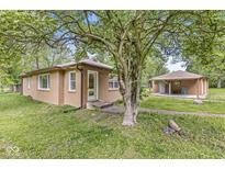 Charming exterior view of a brick house and patio, shaded by a large tree in a lush green yard at 6401 N Oakland Ave, Indianapolis, IN 46220