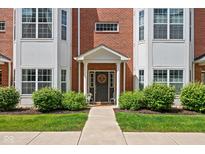 Charming home featuring a welcoming front door, brick facade, manicured lawn, and lush landscaping at 863 N Park Trail Dr, Carmel, IN 46032