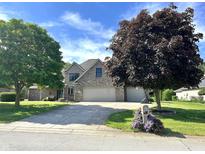 Well-maintained brick house with a three-car garage, mature trees, and a sunny sky above at 941 W Barouche, Pendleton, IN 46064