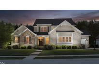 Beautiful two-story home with a stone and brick facade, manicured lawn, and professional landscaping at twilight at 14003 Grannan Ln, Carmel, IN 46074