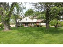 Front view of a two-story home with brick and siding, mature trees, and lush green lawn at 15203 Shoreway Ct, Carmel, IN 46032