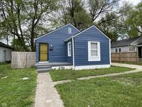 Charming blue bungalow with a yellow security door and well-maintained lawn at 2324 E 36Th St, Indianapolis, IN 46218