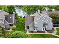 Charming grey two-story home with lush green lawn and serene lake view provides an inviting retreat at 2829 Somerset Bay, Indianapolis, IN 46240