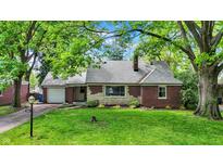 Charming brick home featuring a well-maintained lawn and lush green trees at 5840 Brouse Ave, Indianapolis, IN 46220