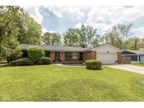 Charming brick ranch-style home with a well-manicured lawn and mature trees at 8415 Los Robles Rd, Fishers, IN 46038