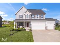 Charming two-story home featuring gray siding, a three-car garage, well-manicured lawn and stone accents at 13410 Mancroft Dr, Fishers, IN 46037