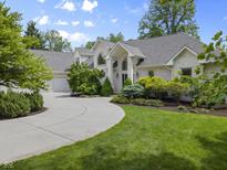 Charming brick home featuring a circular driveway, manicured lawn, and lush landscaping at 13909 Springmill Rd, Carmel, IN 46032