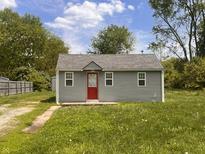 Charming single-story home featuring a red front door and freshly painted exterior in a serene, green yard at 1605 S Whittier Pl, Indianapolis, IN 46203