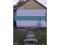 Shows the partially renovated exterior featuring horizontal siding, concrete block foundation, and an A-frame roof at 2134 Dr Andrew J Brown Ave, Indianapolis, IN 46202
