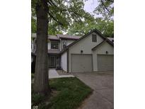Two-story home with a two-car garage and neutral siding surrounded by mature trees and lush landscaping at 11506 Hidden Bay, Indianapolis, IN 46236