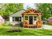 Charming home with a gabled facade, a wooden porch, and a well-manicured lawn at 1240 E 56Th St, Indianapolis, IN 46220
