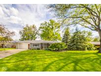 Charming single-story home with a lush green lawn and mature trees creating a picturesque setting at 2319 E 40Th St, Anderson, IN 46013