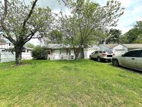Ranch-style home featuring a well-maintained lawn, mature trees, and two driveways leading to attached garages at 2337 N Webster N Ave, Indianapolis, IN 46219